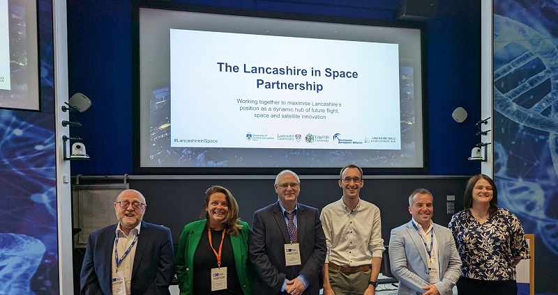 A line up of professors and partners involved in the space programme, in front of a large screen with the wording 'The Lancashire in Space Partnership'  with the associated partner logos. 